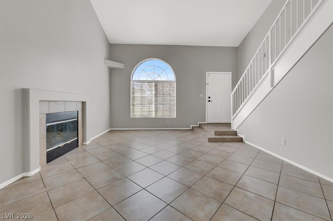 10148 Tree Bark Street Las Vegas, NV 89183 - Photo 6 of 37 A well-lit living area features tiled flooring, a cozy fireplace, and an arched window.