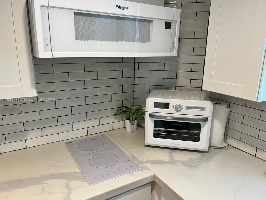 820 3rd Street, Unit 3 Miami Beach, FL 33139 - Photo 17 of 24 a kitchen with granite countertop white cabinets and stainless steel appliances