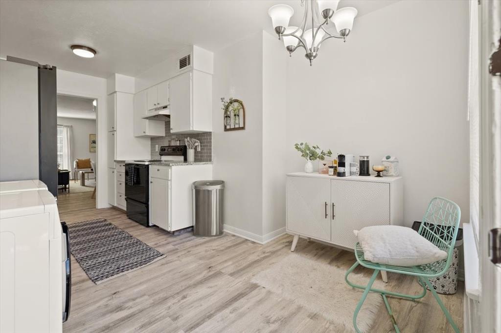 4100 Ridglea Country Club Drive, Unit 1401 Fort Worth, TX 76126 - Photo 12 of 27 a living room with kitchen island a wooden floor and a chandelier