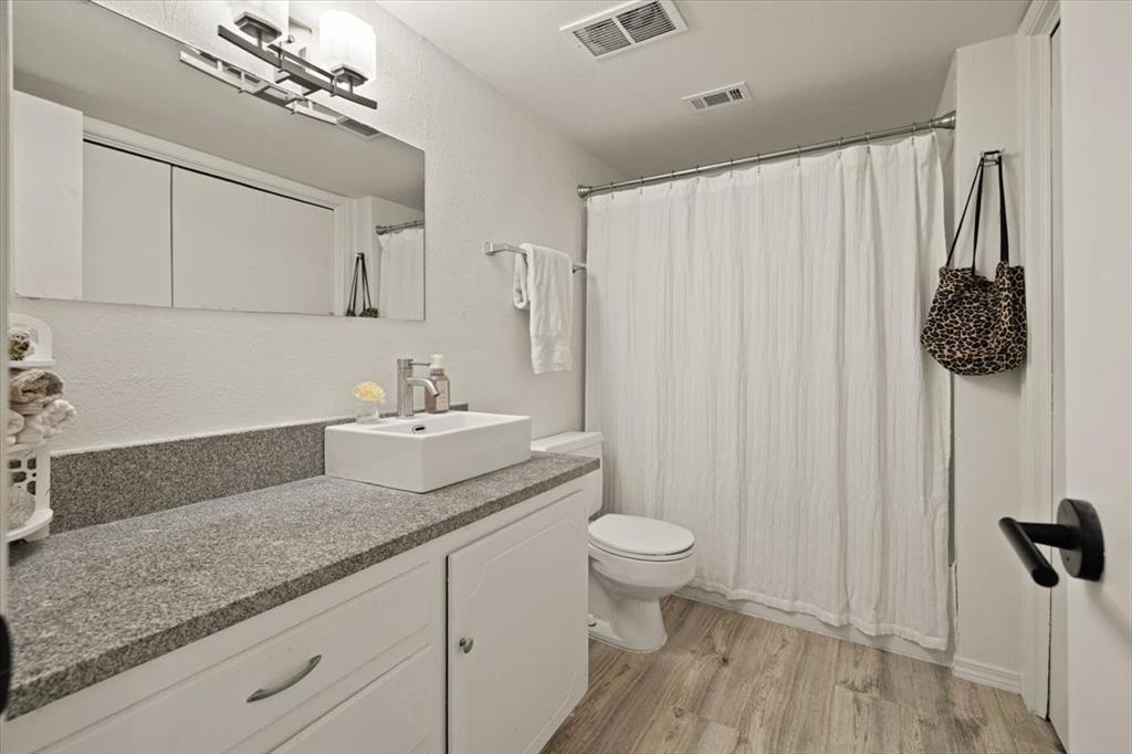 4100 Ridglea Country Club Drive, Unit 1401 Fort Worth, TX 76126 - Photo 15 of 27 a bathroom with a granite countertop sink a toilet and a mirror