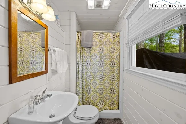 a bathroom with a sink a toilet a mirror and shower