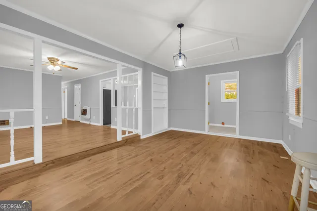 a view of empty room with wooden floor and fan