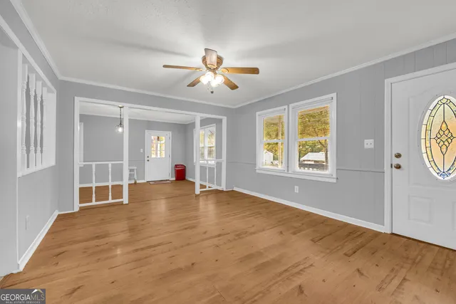 a view of an empty room with window and a ceiling fan