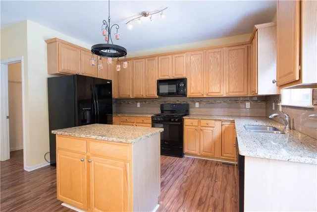 a kitchen with stainless steel appliances granite countertop a refrigerator a stove top oven a sink and dishwasher with wooden floor