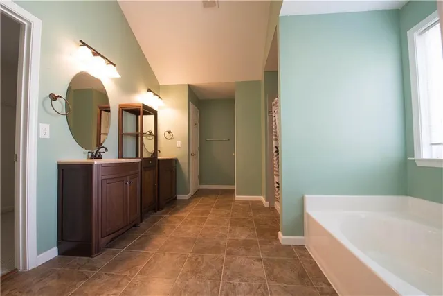 a bathroom with a tub a mirror and a sink