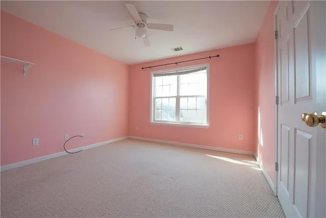 an empty room with a window and ceiling fan