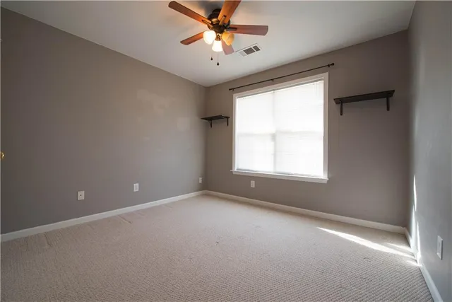 an empty room with a window and a ceiling fan