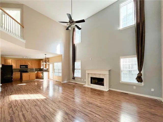 an empty room with wooden floor fireplace and windows