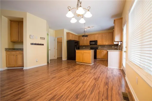 a open kitchen with cabinets wooden floor and stainless steel appliances