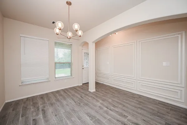 an empty room with wooden floor cabinet and windows