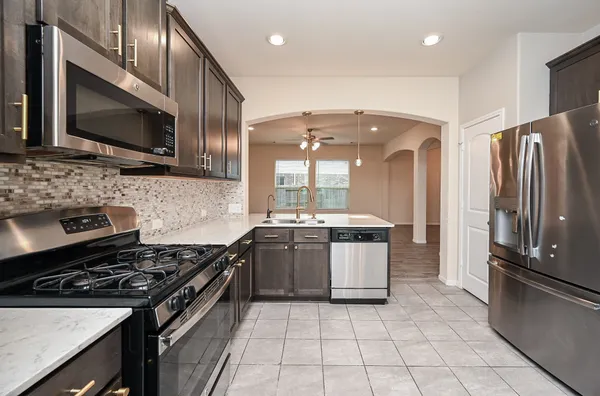 a kitchen with stainless steel appliances granite countertop a stove microwave and refrigerator