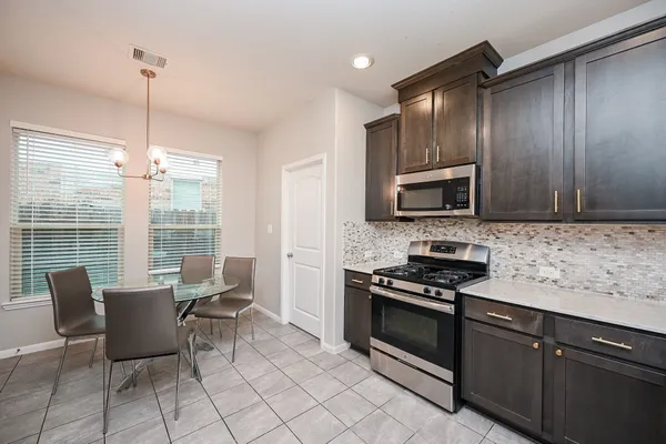 a kitchen with granite countertop a stove a sink and a microwave