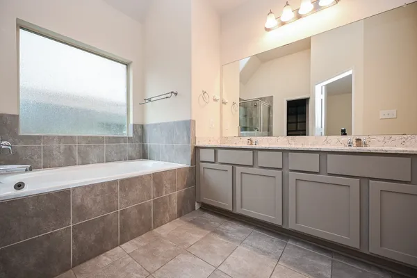 a spacious bathroom with a double vanity sink a mirror and a bathtub
