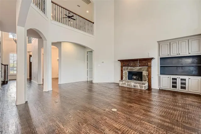 a view of an empty room with wooden floor and a fireplace