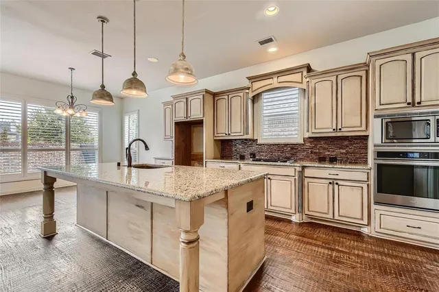 a kitchen with stainless steel appliances granite countertop a sink a stove and a wooden floor