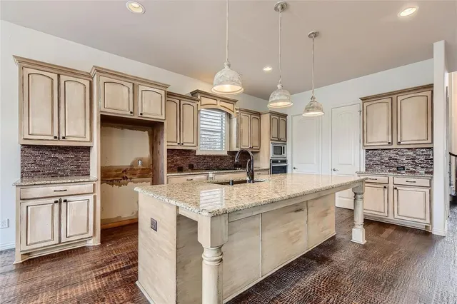 a kitchen with kitchen island granite countertop a stove cabinets and wooden floor