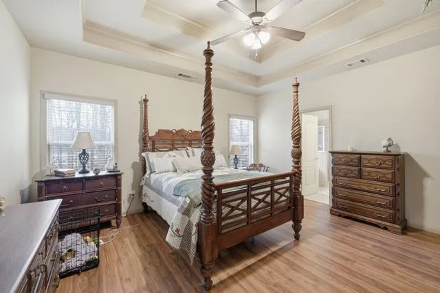 a spacious bedroom with a bed a chandelier and a dresser