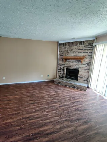 an empty room with wooden floor fireplace and windows