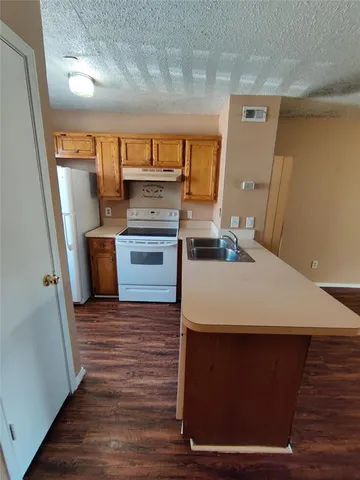 a room with kitchen island a stove a sink and a refrigerator