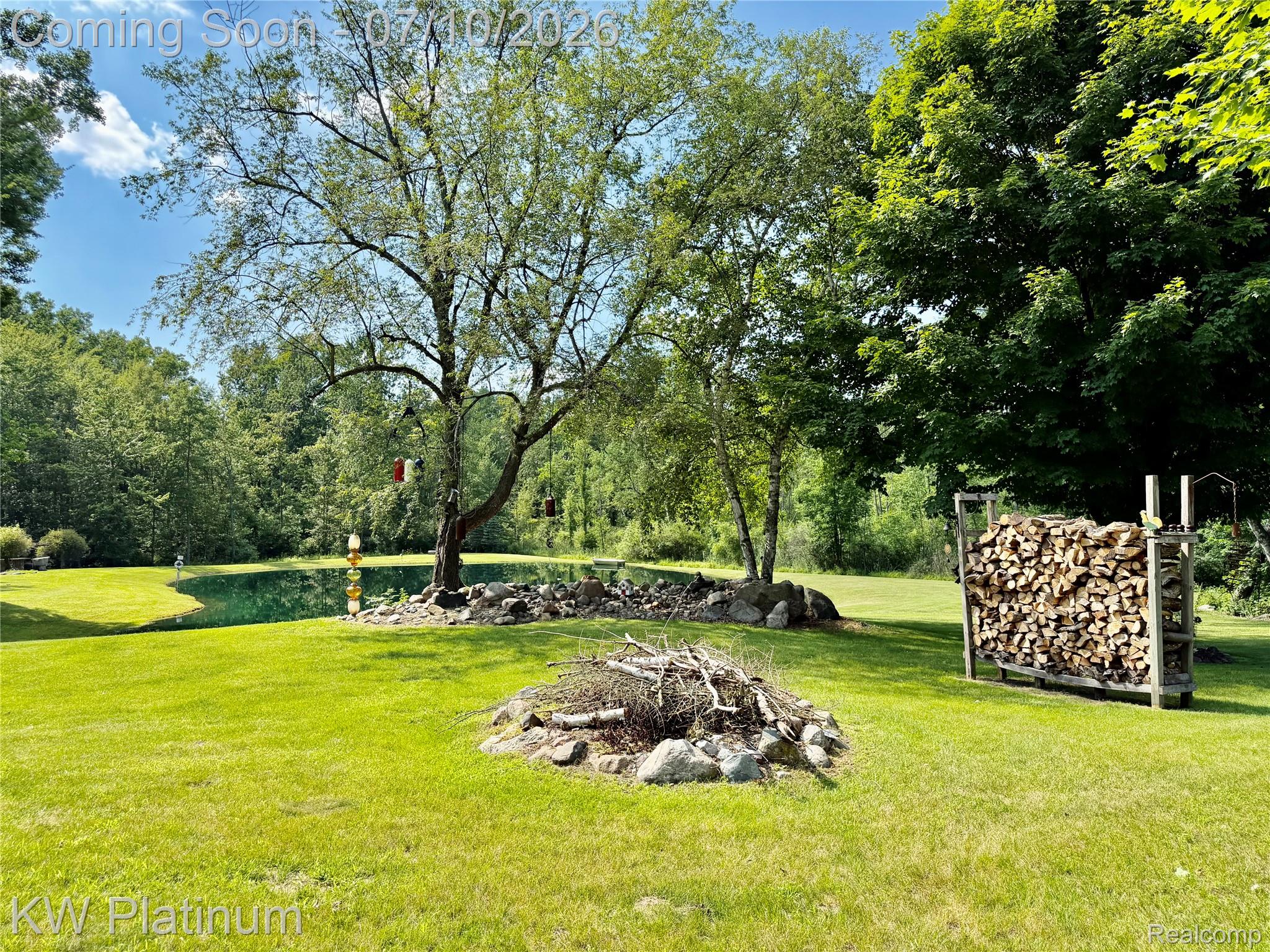 1581 Emerson Road Goodells, MI 48027 - Photo 32 of 45 Expansive green lawn with a tranquil pond, surrounded by mature trees