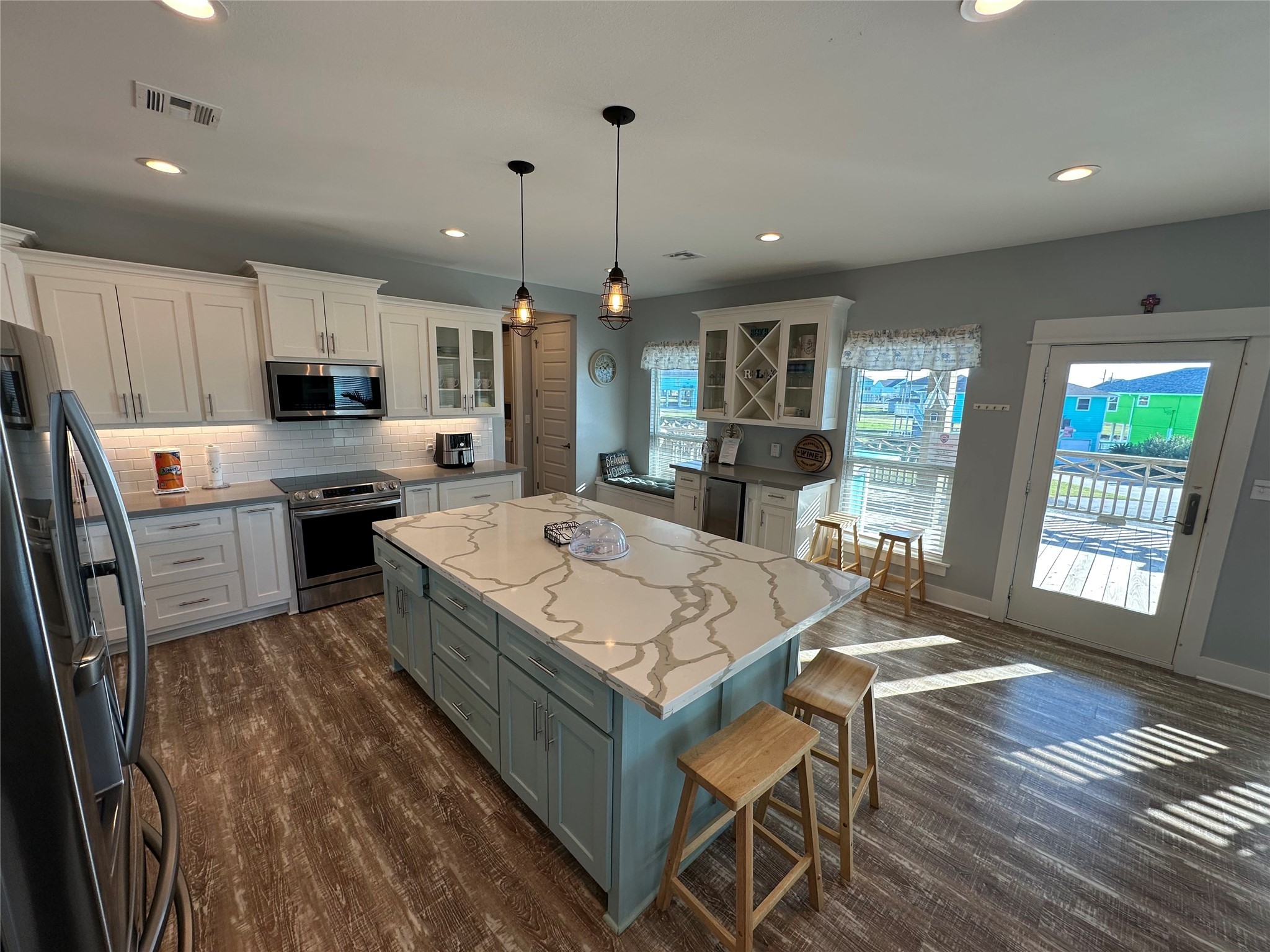 2429 Sand Castle Crystal Beach, TX 77650 - Photo 20 of 46 a large kitchen with kitchen island a stove a sink a refrigerator and a dining table with wooden floor