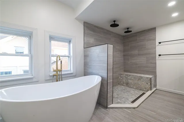a white bath tub sitting in a bathroom next to a window