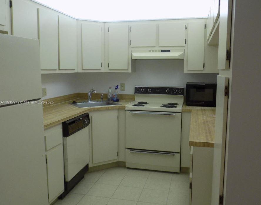 824 Sky Pine Way, Unit A1 West Palm Beach, FL 33415 - Photo 4 of 9 a kitchen with a stove a sink and cabinets