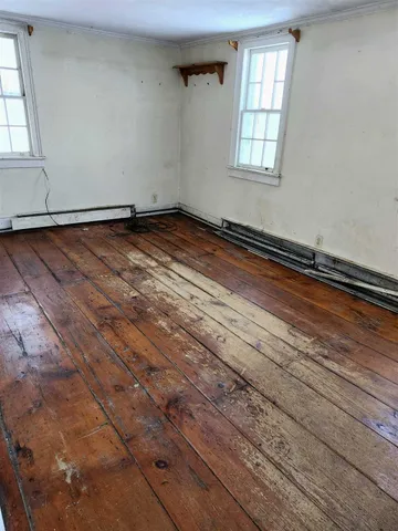 a view of empty room with window and wooden floor