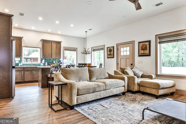 a living room with couches and kitchen view with wooden floor