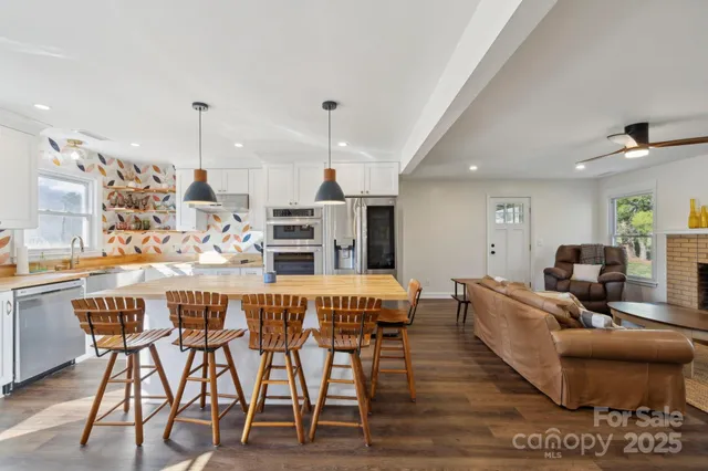 a kitchen with stainless steel appliances kitchen island granite countertop a table chairs in it and wooden floors
