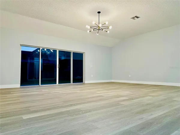 an empty room with wooden floor ceiling fan and windows
