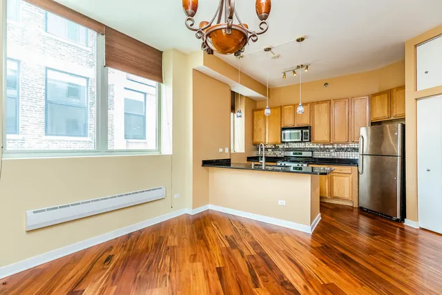 a kitchen with granite countertop wooden floors stainless steel appliances and a window