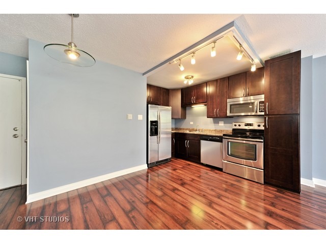 2930 North Sheridan Road, Unit 511 Chicago, IL 60657 - Photo 6 of 10 a kitchen with granite countertop a refrigerator and a stove