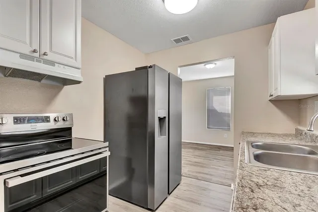 a kitchen with granite countertop a refrigerator and a sink