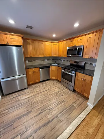a kitchen with stainless steel appliances granite countertop a stove a sink and a refrigerator