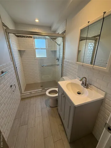 a bathroom with a sink a toilet a mirror and shower