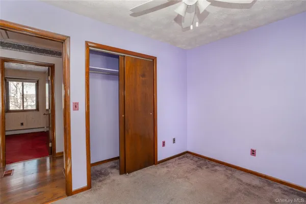 an empty room with wooden floor chandelier fan and windows