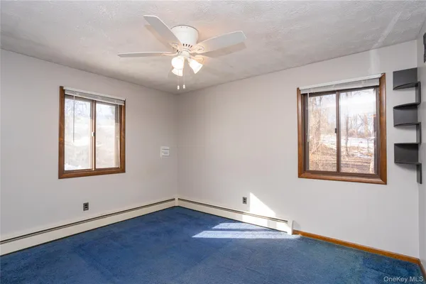 an empty room with wooden floor chandelier fan and windows