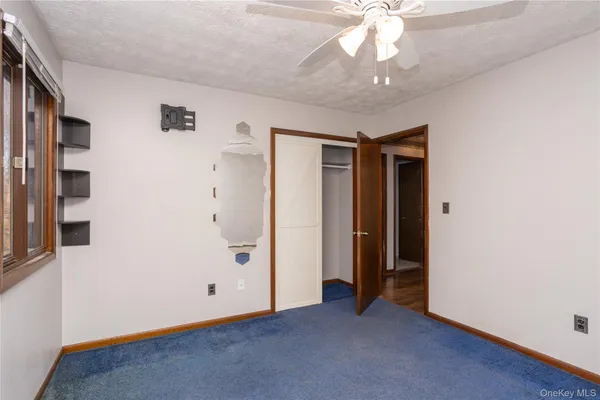 an empty room with a chandelier fan and windows