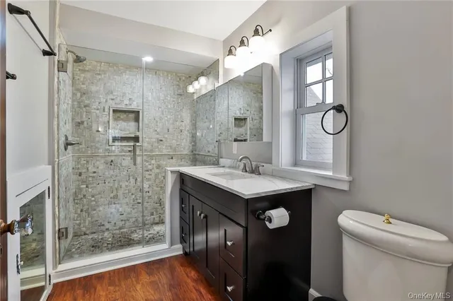 a bathroom with a granite countertop sink a toilet a mirror and shower