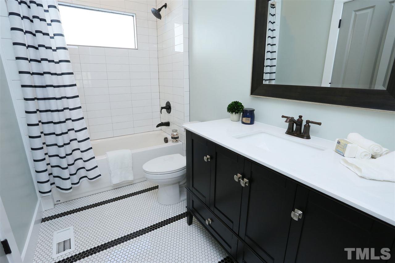 1007 South Person Street Raleigh, NC 27601 - Photo 17 of 25 This main floor bathroom is accessible from the north bedroom as well as the downstairs hall. Its penny tile floor is a nod to the home's traditional roots.