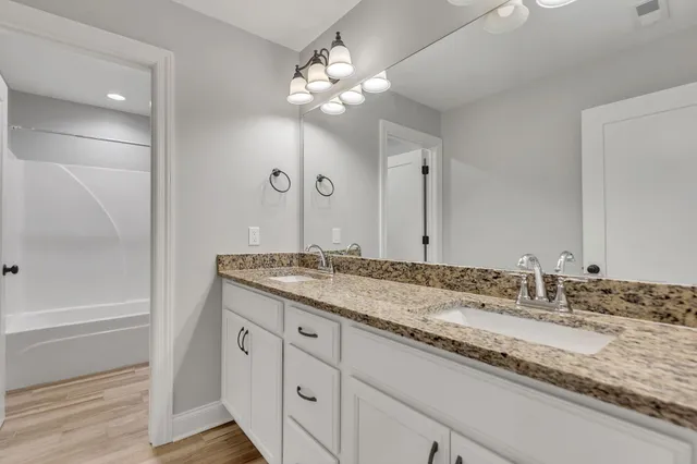 a bathroom with a granite countertop sink a large mirror and a shower