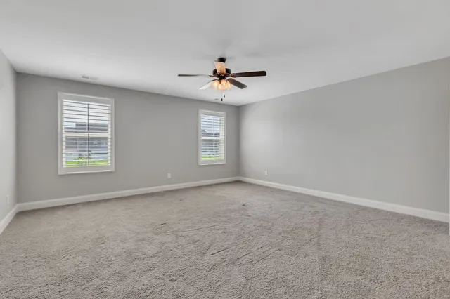 an empty room with windows and chandelier fan