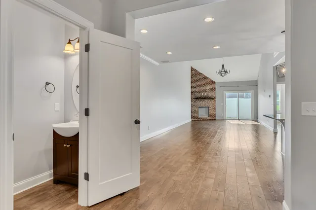 a view of an empty room with wooden floor and a bathroom