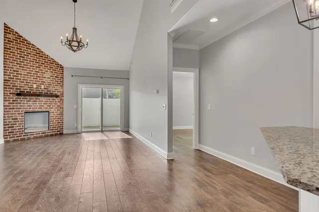 an empty room with wooden floor fireplace and windows