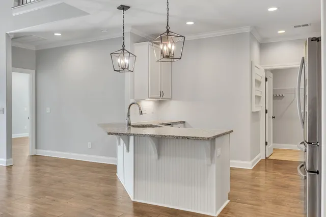 a view of a kitchen with a sink stainless steel appliances and chandelier