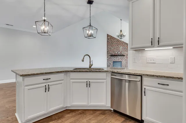 a kitchen with white cabinets stainless steel appliances and window