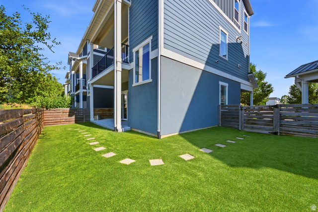 862 Founders Point Lane South Midvale, UT 84047 - Photo 33 of 45 Expansive backyard featuring artificial turf, stepping stones, a wooden retaining wall, and horizontal slat fencing