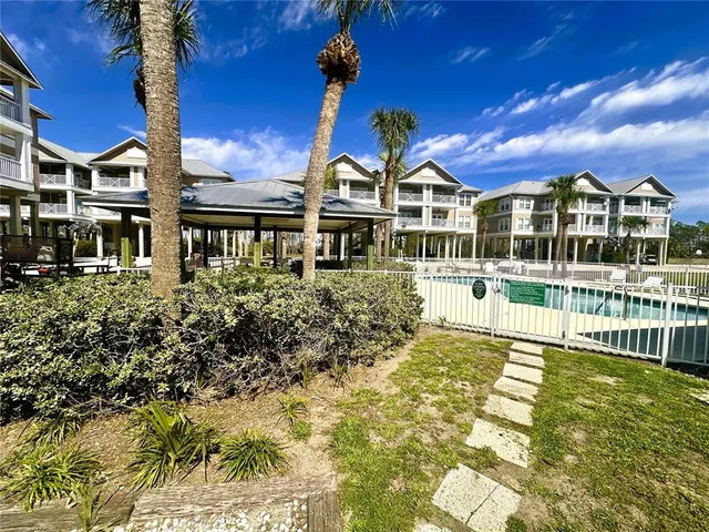 a front view of a building with a garden and trees