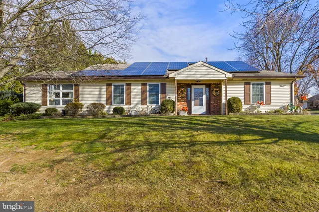 a front view of a house with a garden and trees